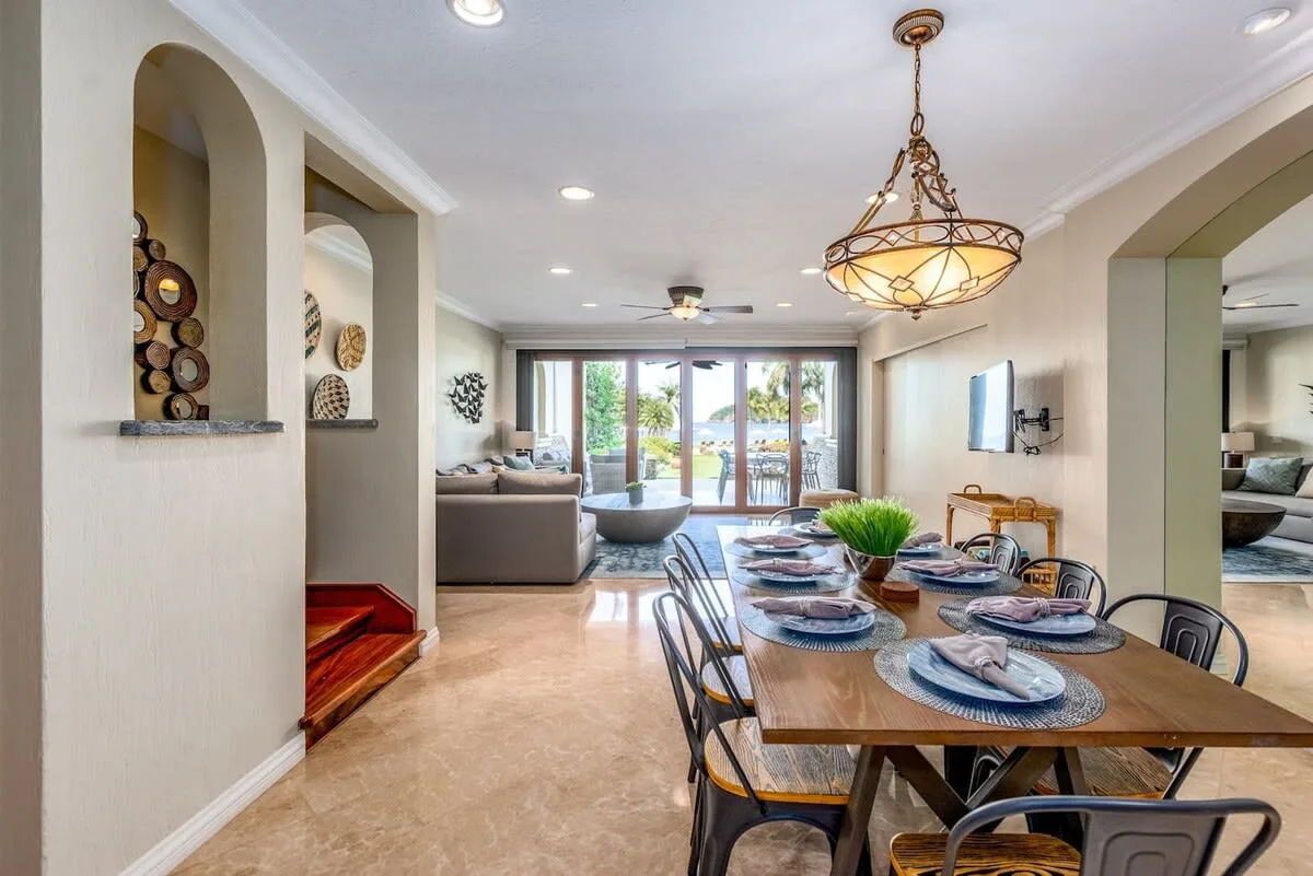 An open-plan dining and living room with a set table and sliding glass doors.