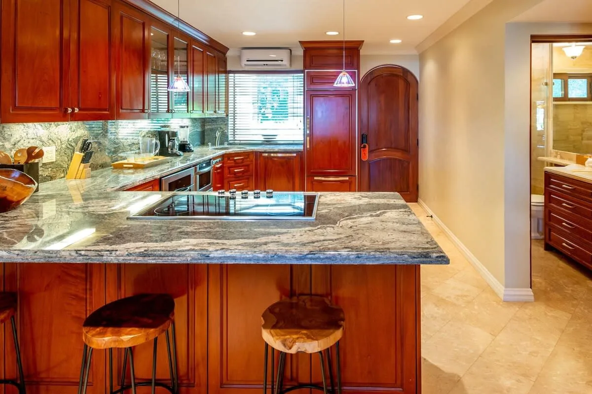 A kitchen with wooden cabinets, a stone countertop, and an island with seating.