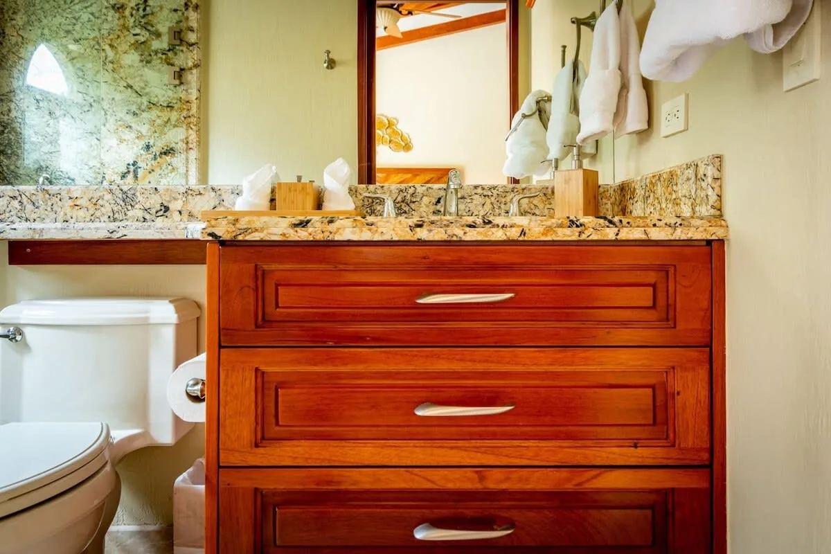 A bathroom vanity with wooden drawers, a countertop, and a mirror.