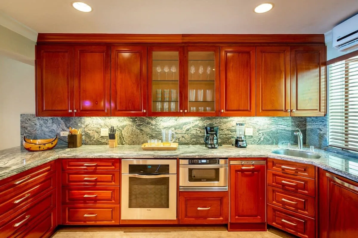 A kitchen with reddish wood cabinets, a built-in oven, and a countertop.