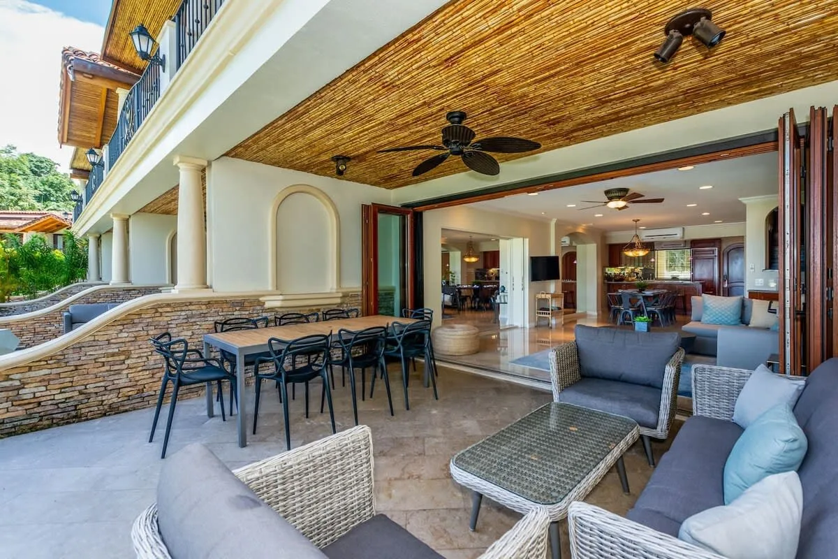 A covered patio with outdoor seating and a dining table opens onto a living area.