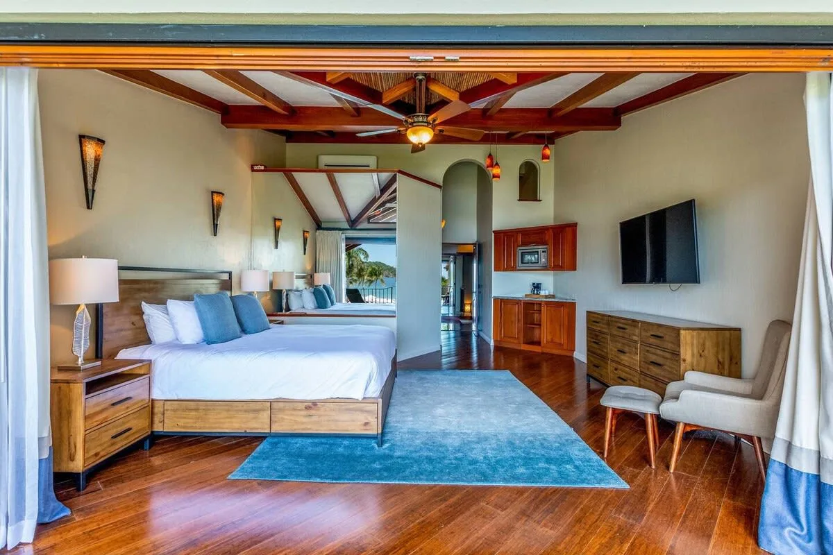 A bedroom with a large bed, blue rug, and wooden furniture.