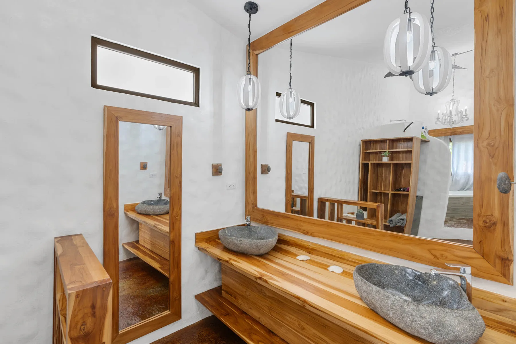 Un tocador de baño con lavabos de piedra y un gran espejo con marco de madera.