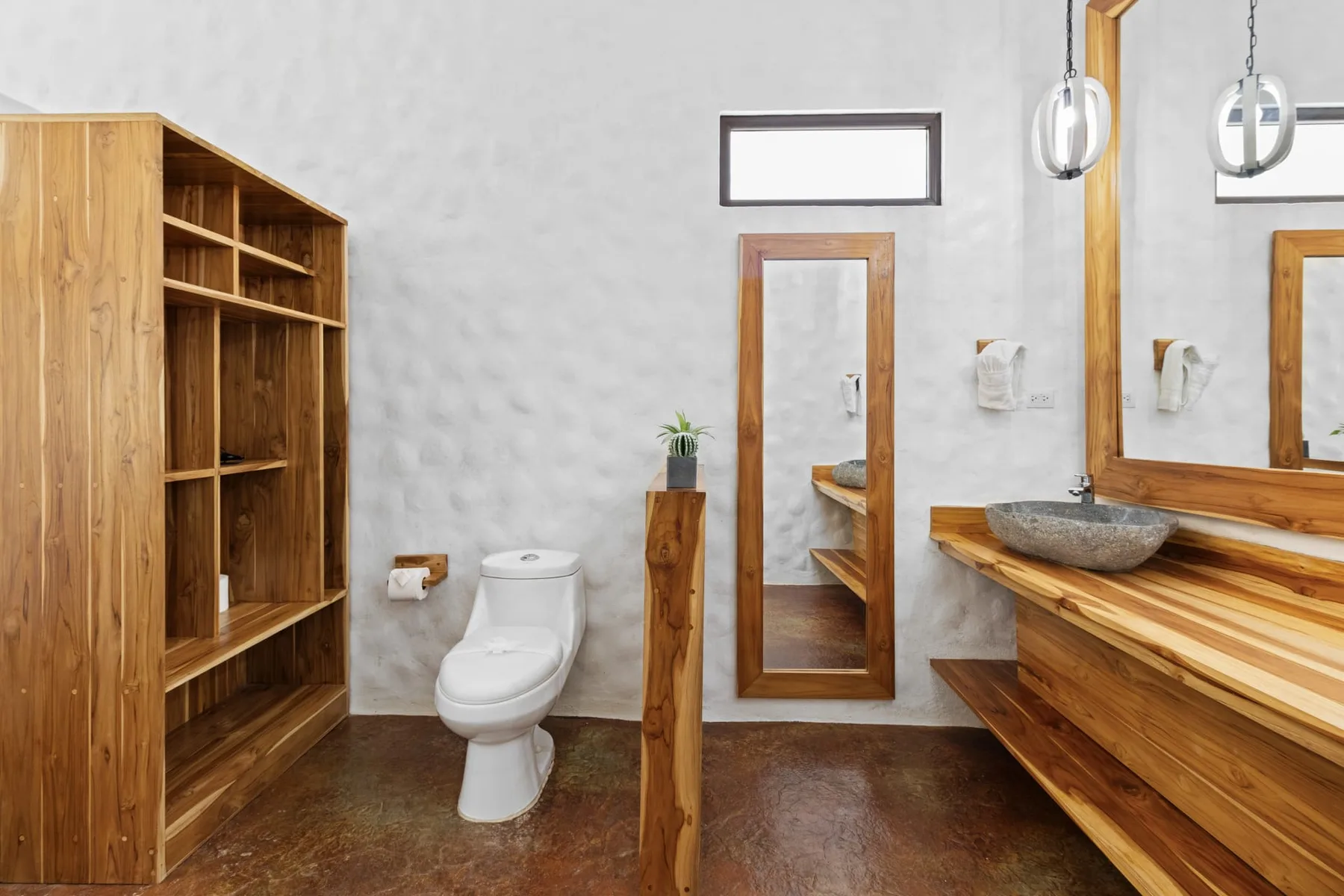 Un baño con tocador de madera, lavabo y estanterías abiertas.