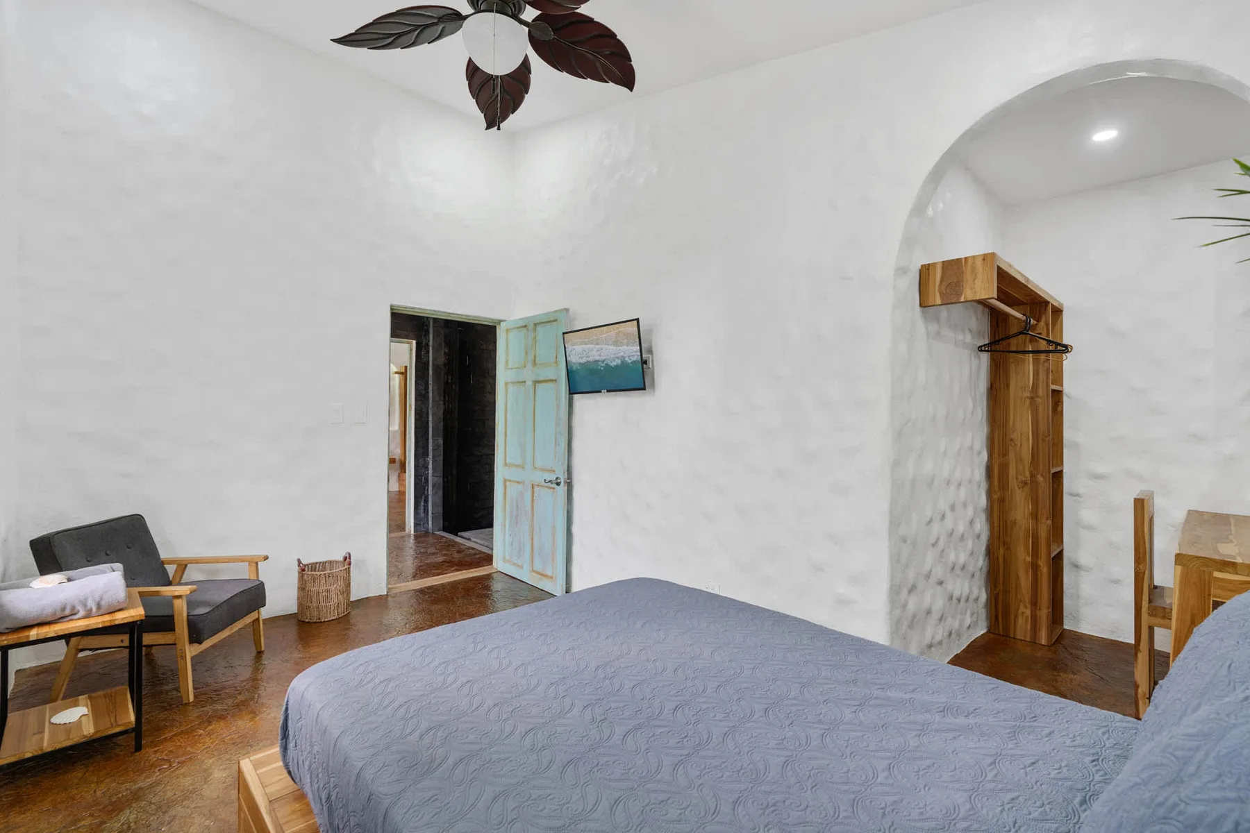 Un dormitorio con una cama, asientos y una puerta abierta.