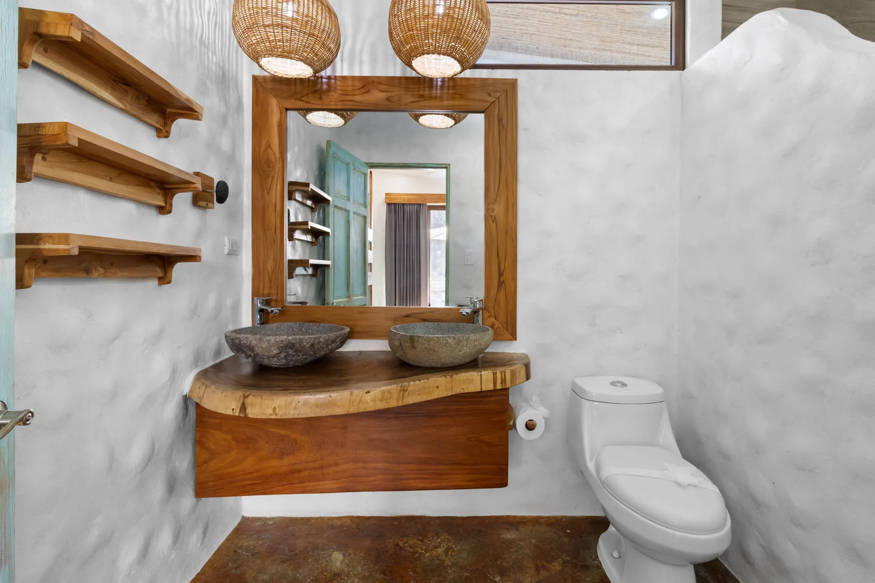Un lavabo de baño con espejo, dos lavabos de recipiente y un inodoro.