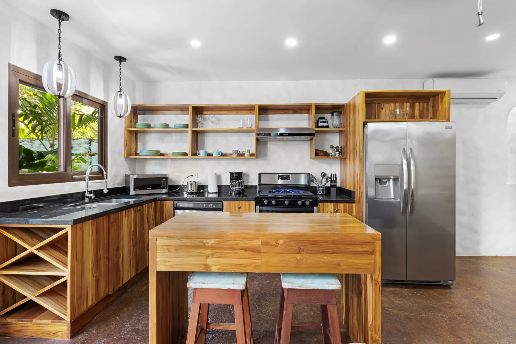 Una cocina con gabinetes de madera, una isla central y electrodomésticos de acero inoxidable.