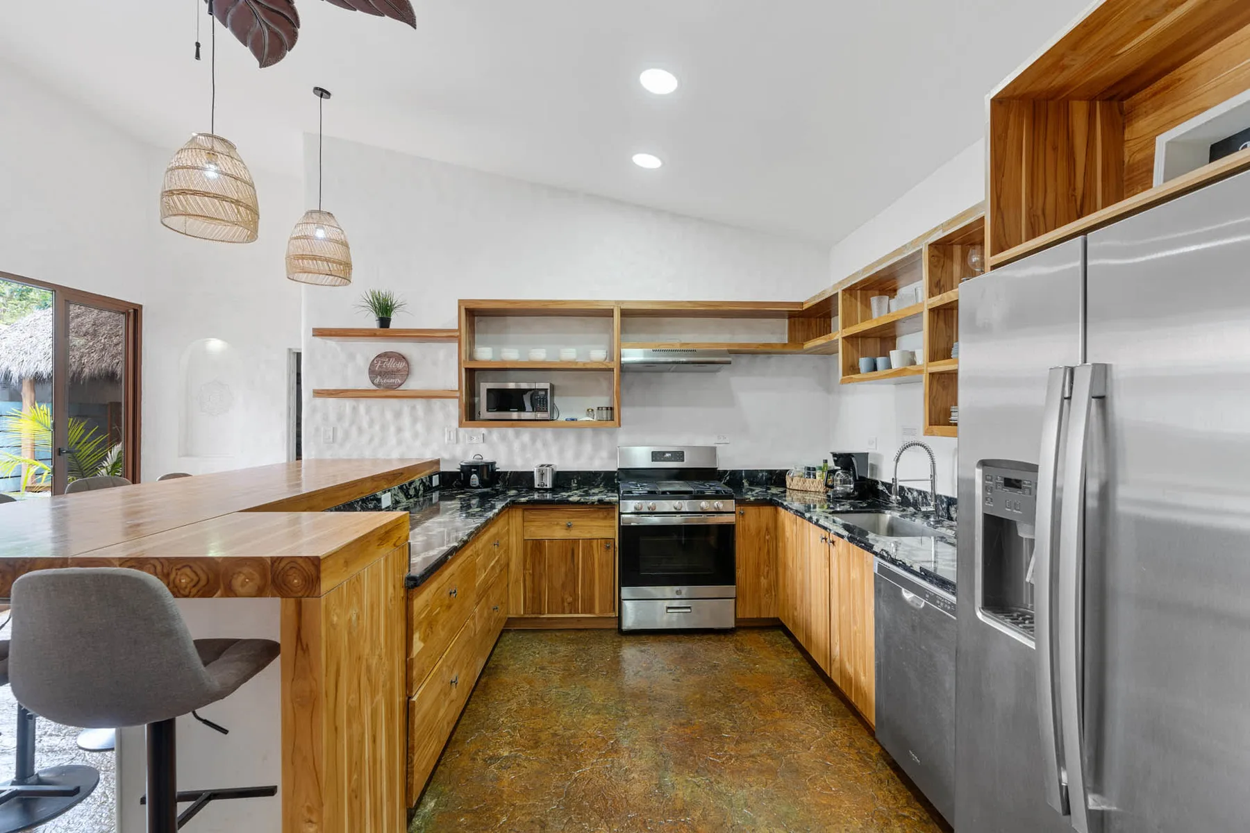 Una cocina con gabinetes de madera, encimeras oscuras y electrodomésticos de acero inoxidable.