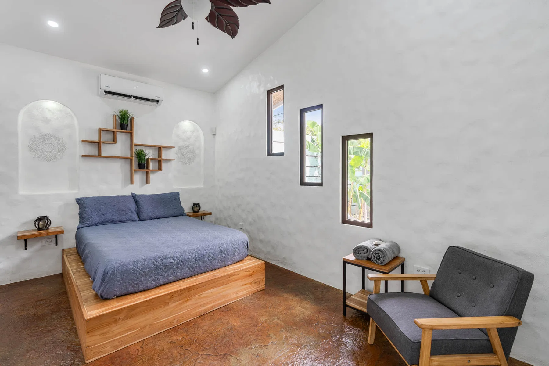Un dormitorio luminoso con una cama de madera y asientos grises.
