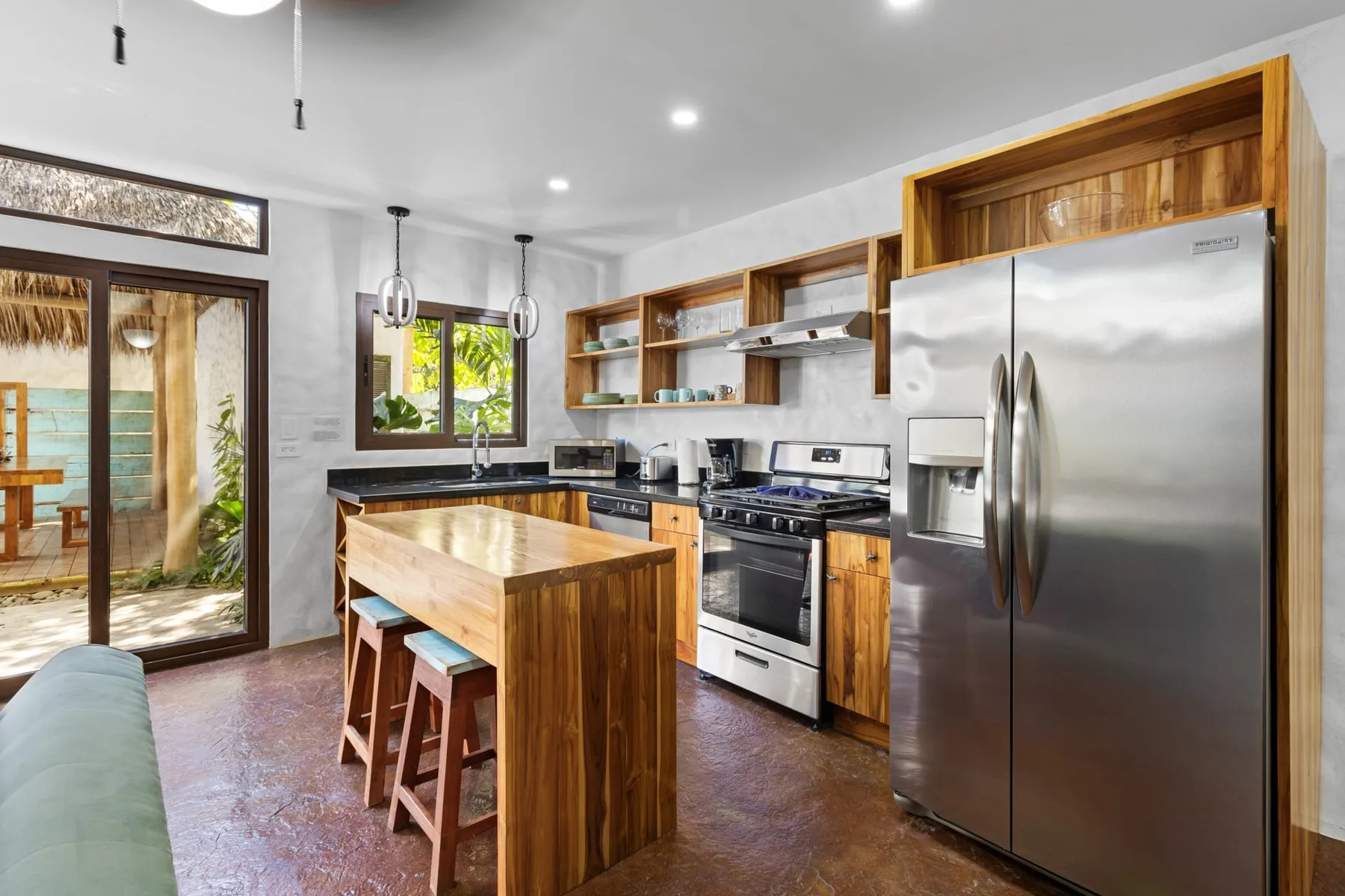 Una cocina luminosa cuenta con una isla de madera, electrodomésticos de acero inoxidable y puertas de vidrio.