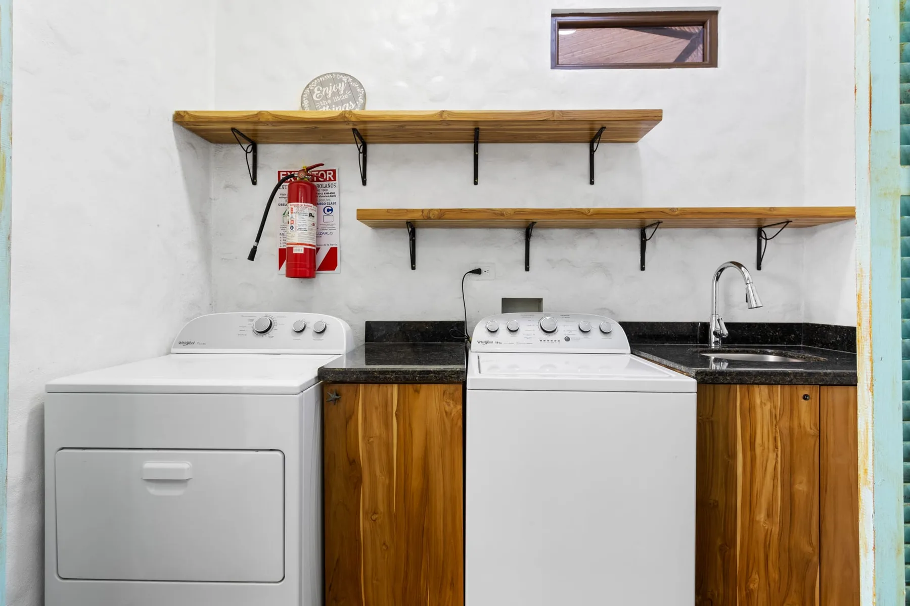 Un cuarto de lavado con dos lavadoras bajo estantes de madera.