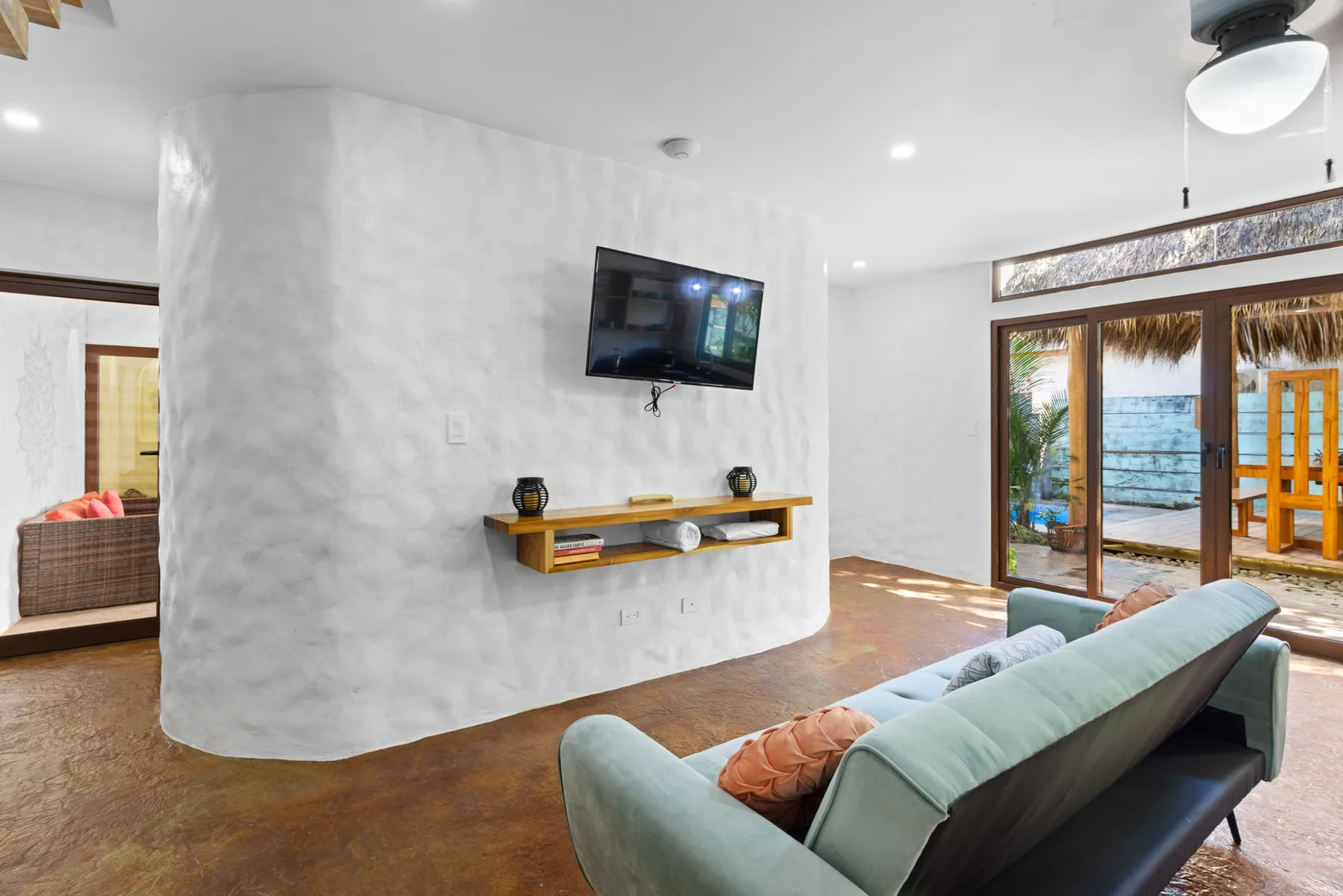 Una sala de estar con un televisor en una pared blanca junto a puertas de vidrio.