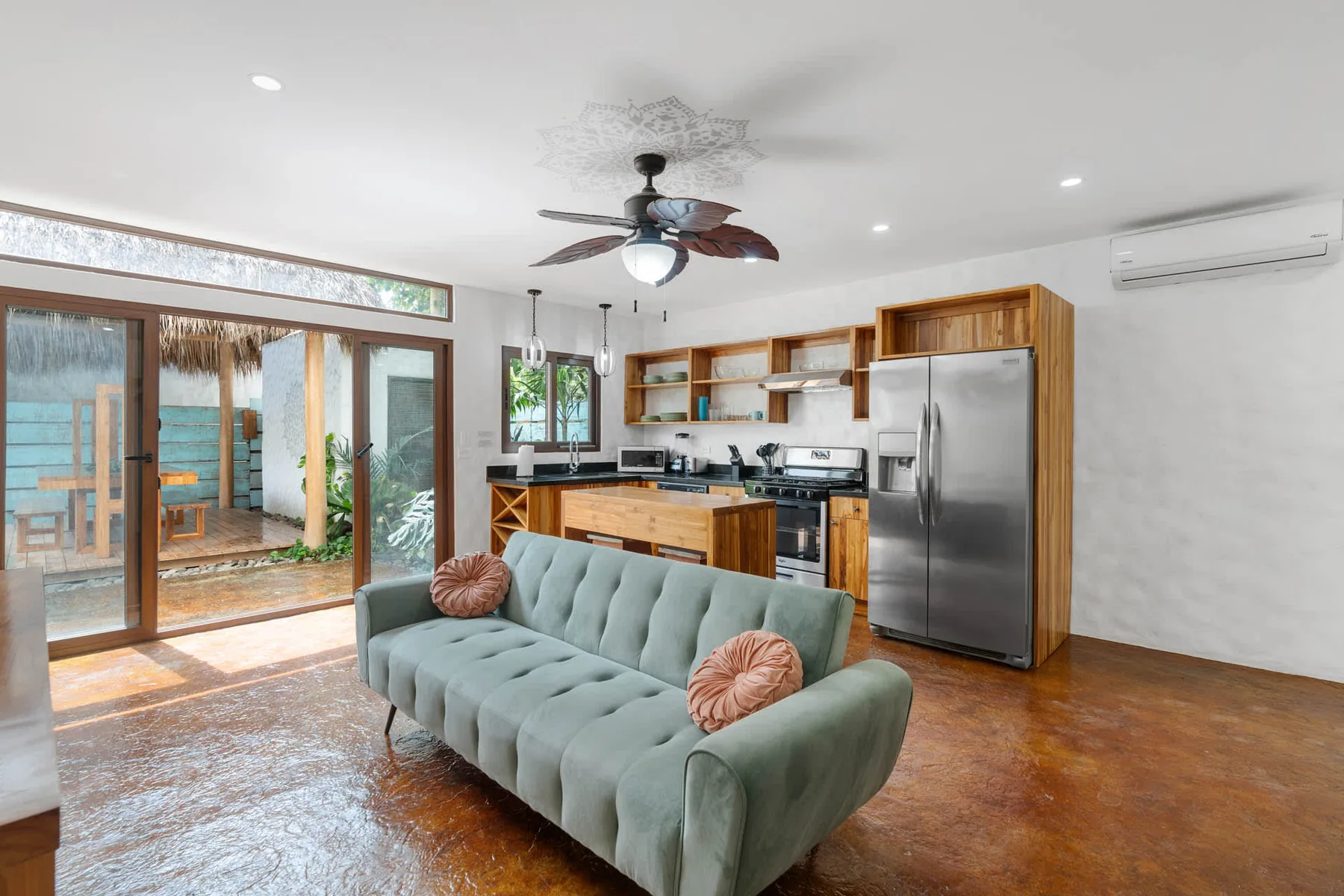 Sala de estar y cocina de planta abierta con puertas corredizas de vidrio a un patio.