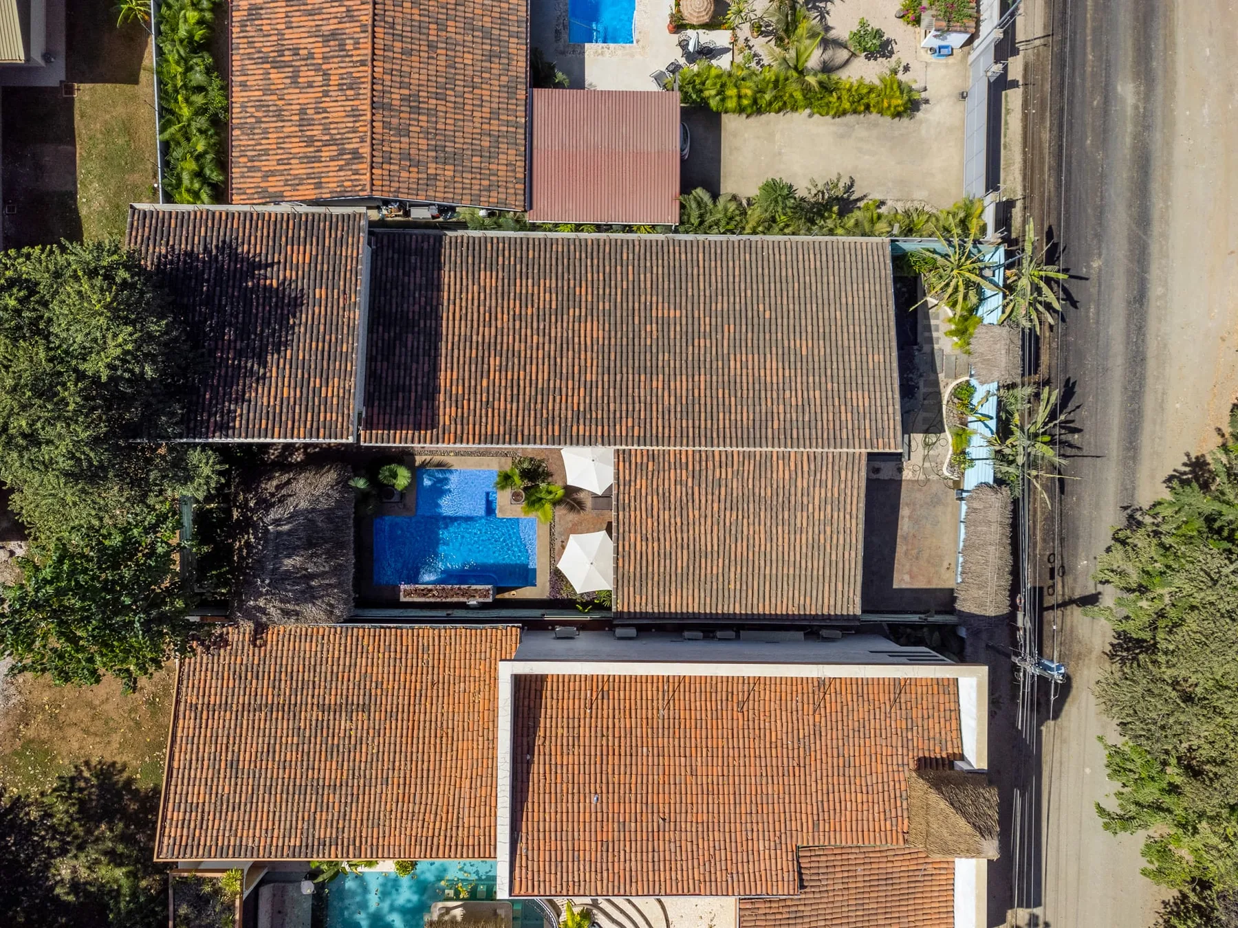 Vista aérea de un conjunto de edificios con tejados de tejas y una piscina.