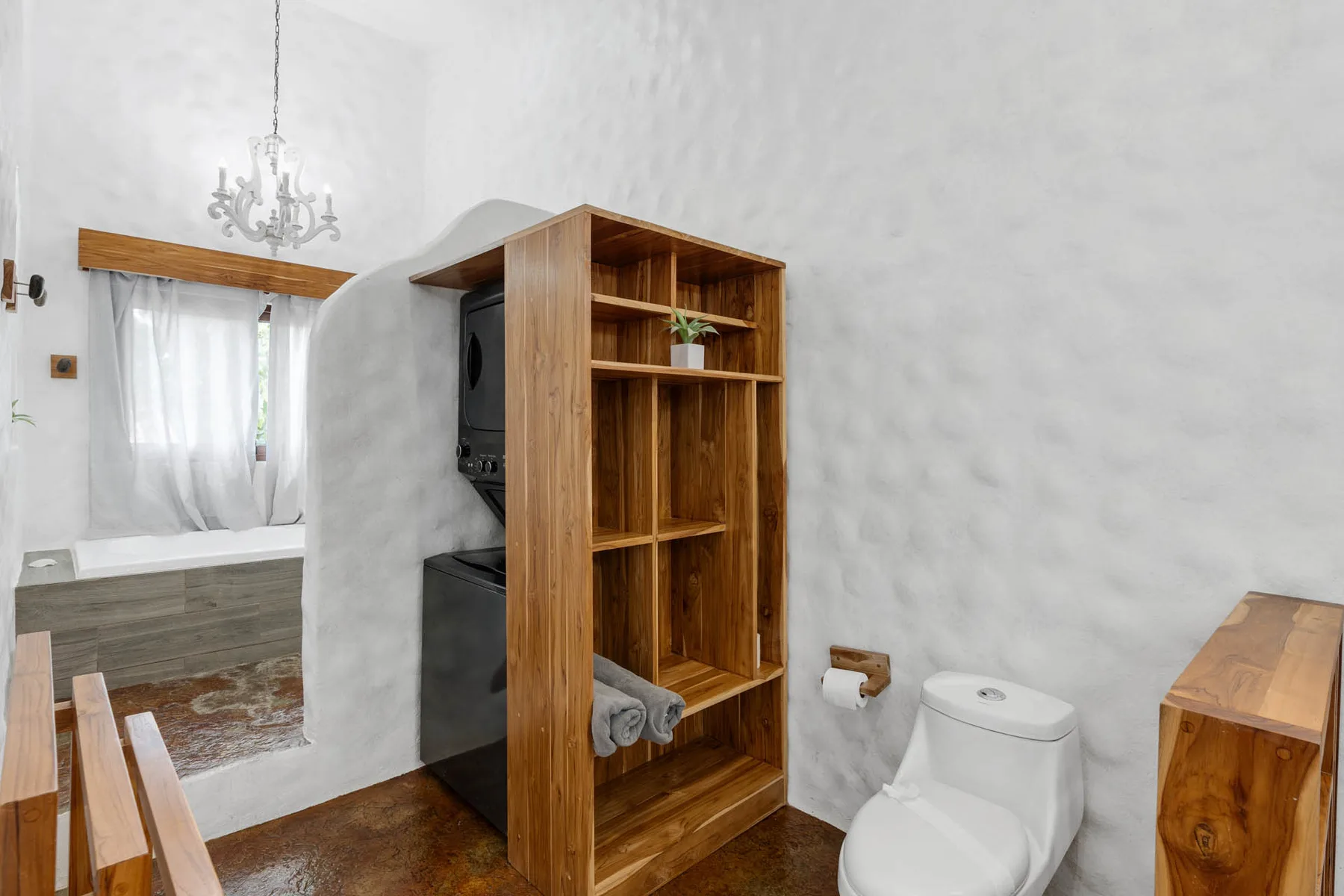 Un baño luminoso con estantes de madera junto al inodoro y la zona de ducha.