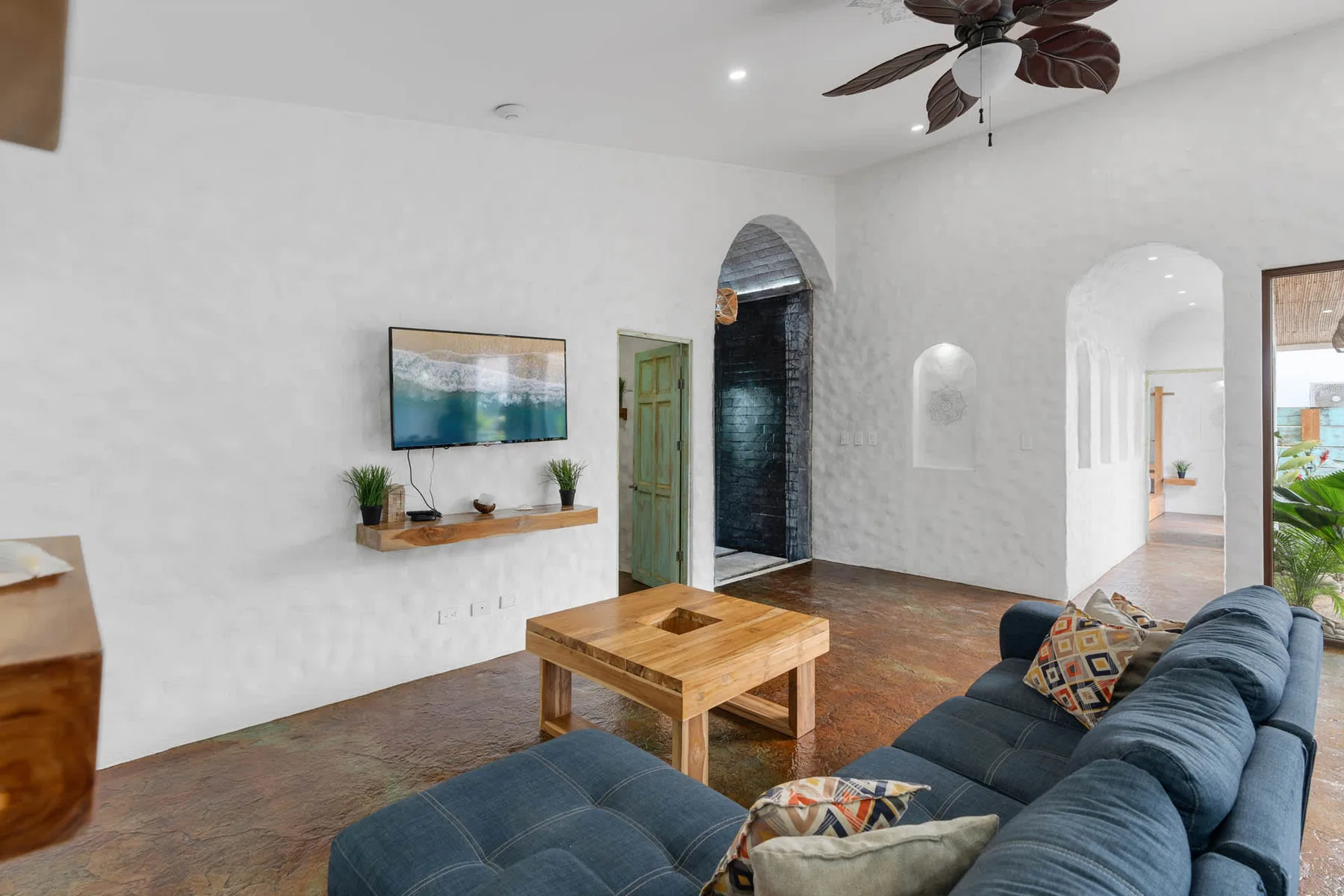 Una sala de estar con asientos azules, una mesa de centro de madera y arcos.