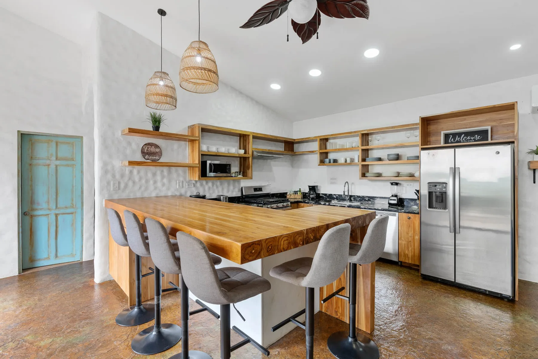 Una cocina luminosa con una gran isla de madera, asientos de barra y electrodomésticos de acero inoxidable.