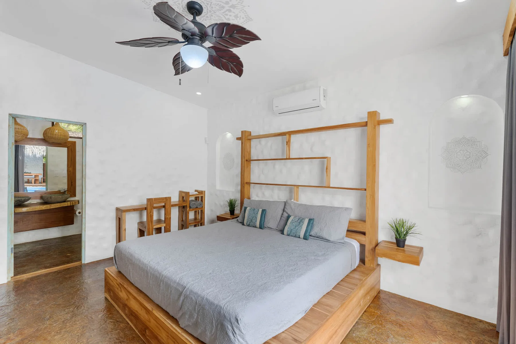 Un dormitorio con una cama de madera, ropa de cama gris y un ventilador de techo.