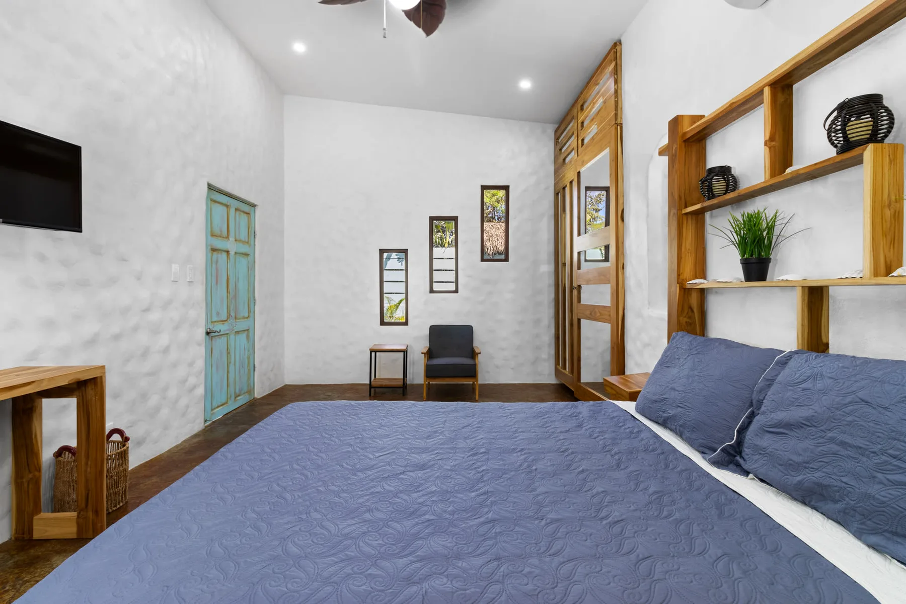 Un dormitorio con una cama grande, un televisor en la pared y estantes de madera.