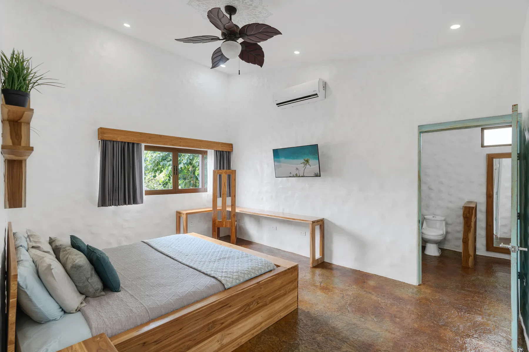 Un dormitorio con una cama de madera, una ventana y una puerta abierta al baño.