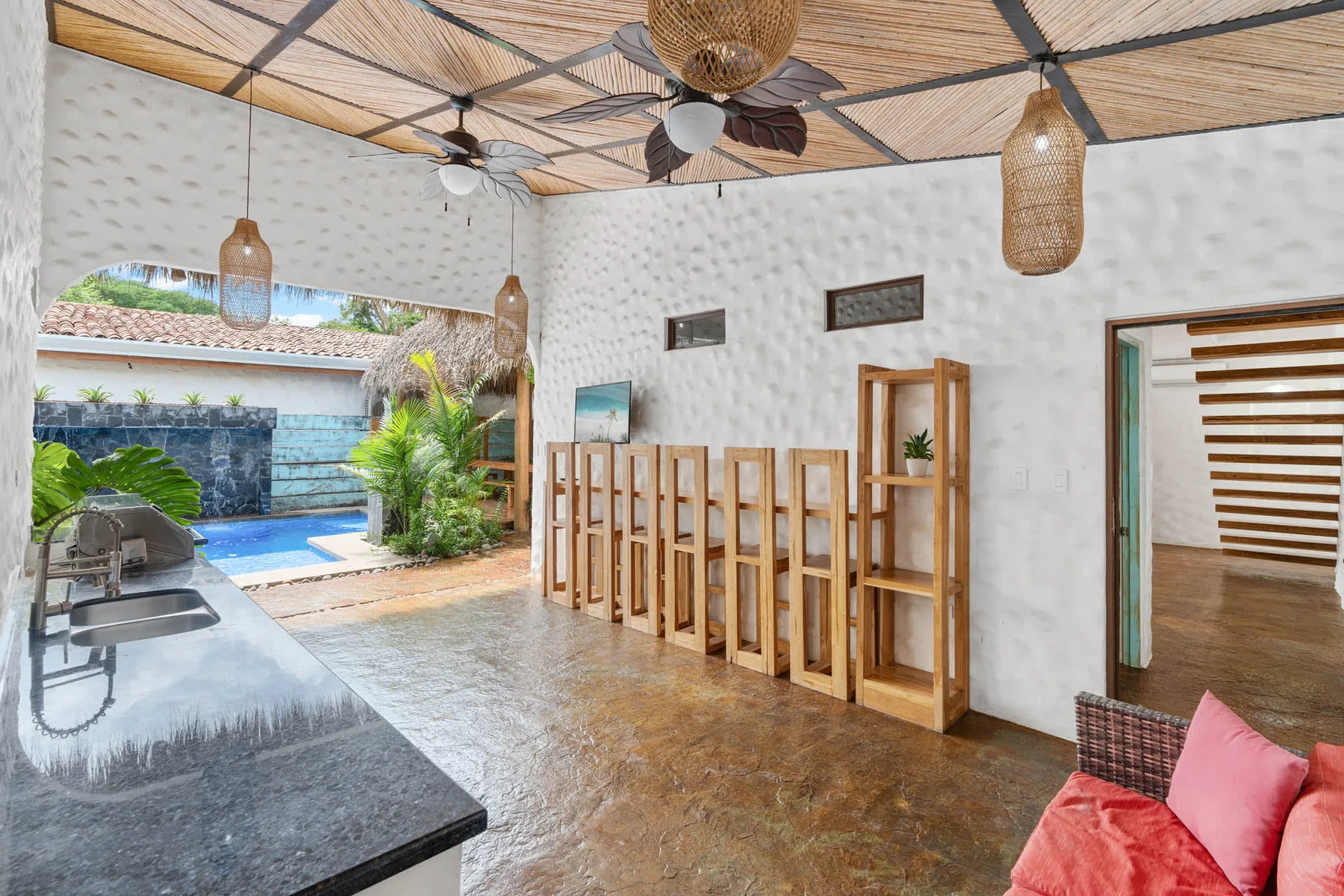 Un patio cubierto con una mesa de comedor, sillas de madera y vistas a la piscina.