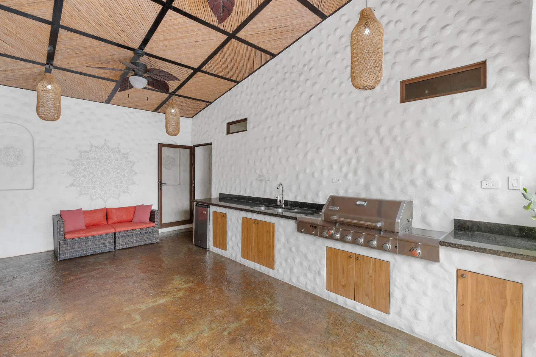 Una cocina exterior cubierta con una encimera larga y una zona de asientos.