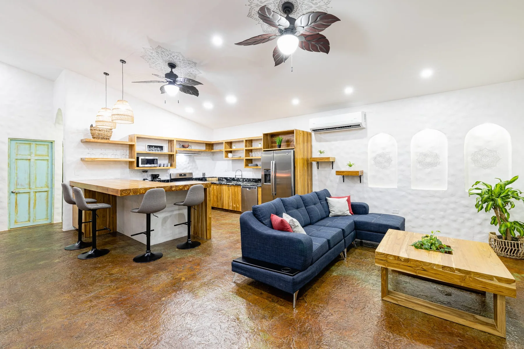 Sala de estar y cocina de planta abierta con sofá seccional azul y barra desayunadora.
