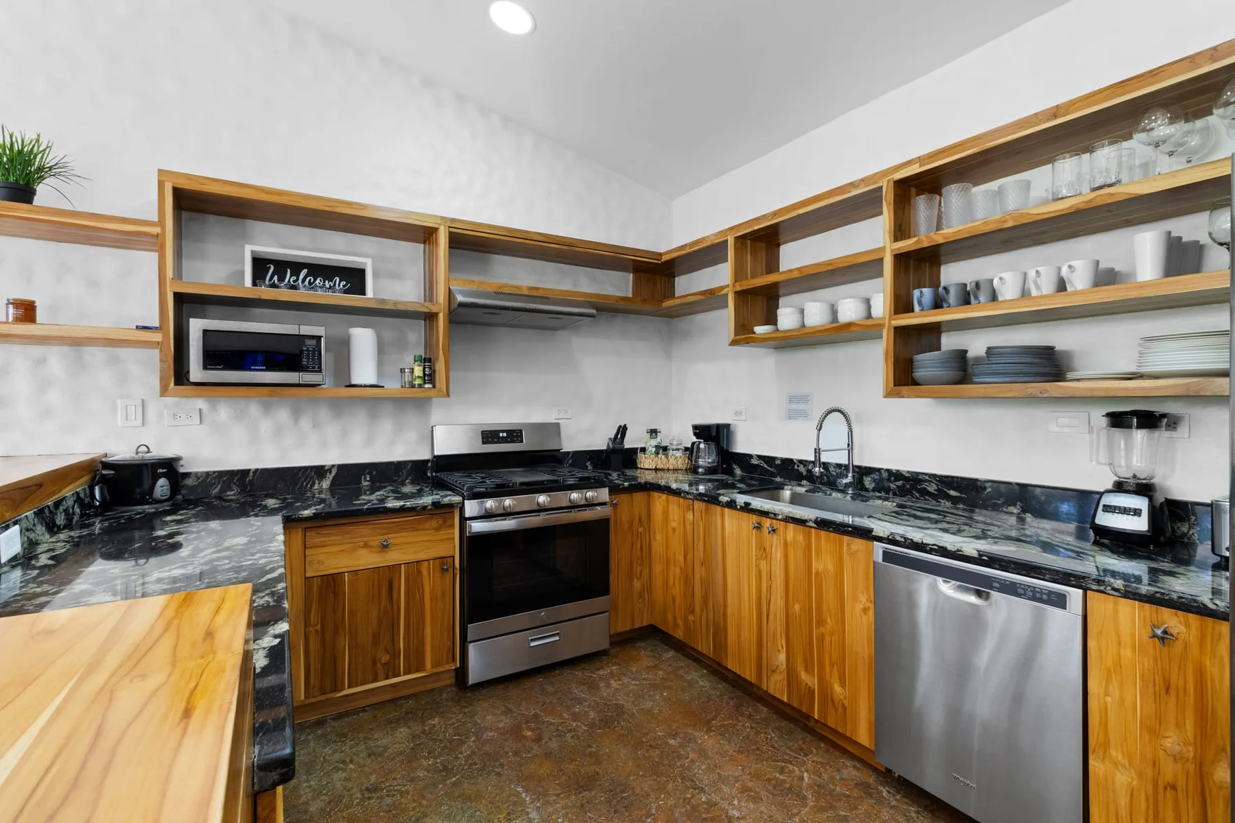 Una cocina con gabinetes de madera, encimeras oscuras y electrodomésticos de acero inoxidable.