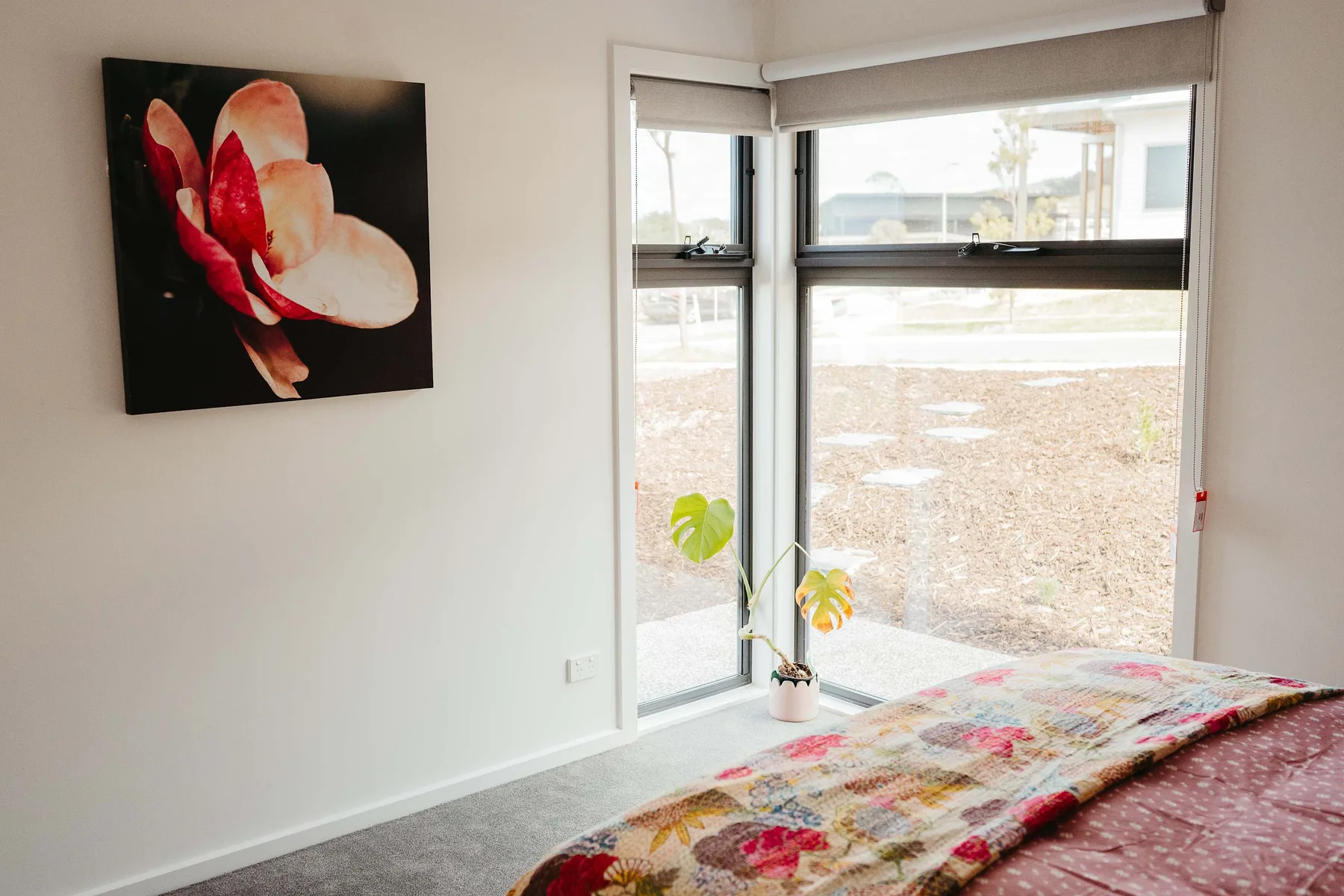 Un dormitorio con una cama junto a grandes ventanas y una planta en maceta.