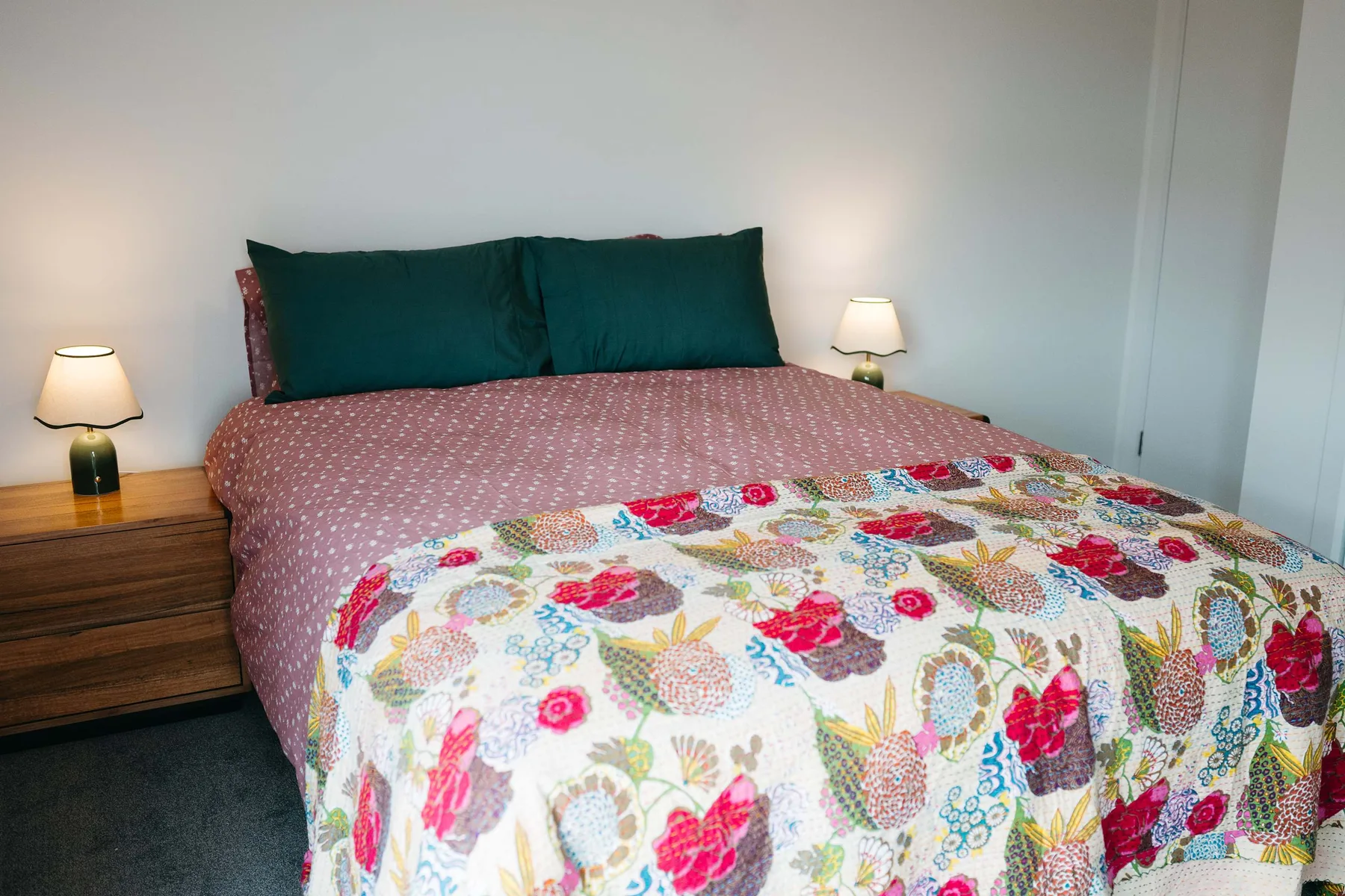 Un dormitorio con una cama cubierta con ropa de cama floral colorida.