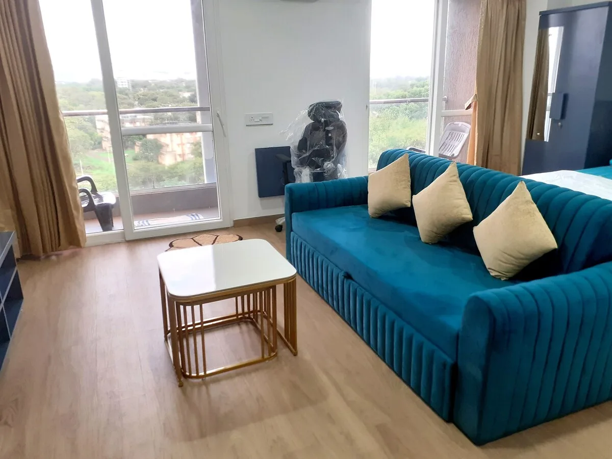 Una sala de estar con asientos color turquesa, una mesa de centro y grandes ventanas.