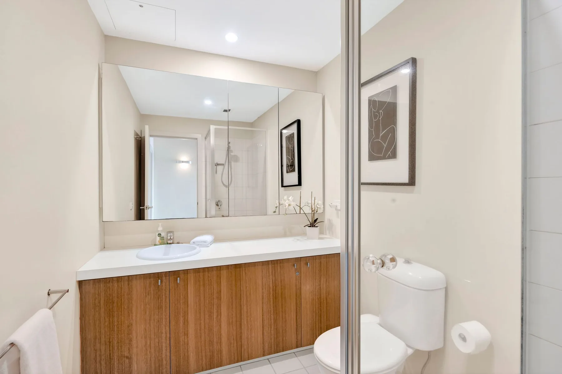 Un lavabo de baño con un espejo amplio y un inodoro al lado.