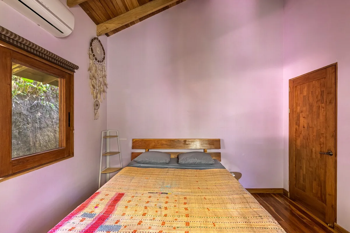 Un dormitorio con una cama de madera, una colcha estampada y una ventana.