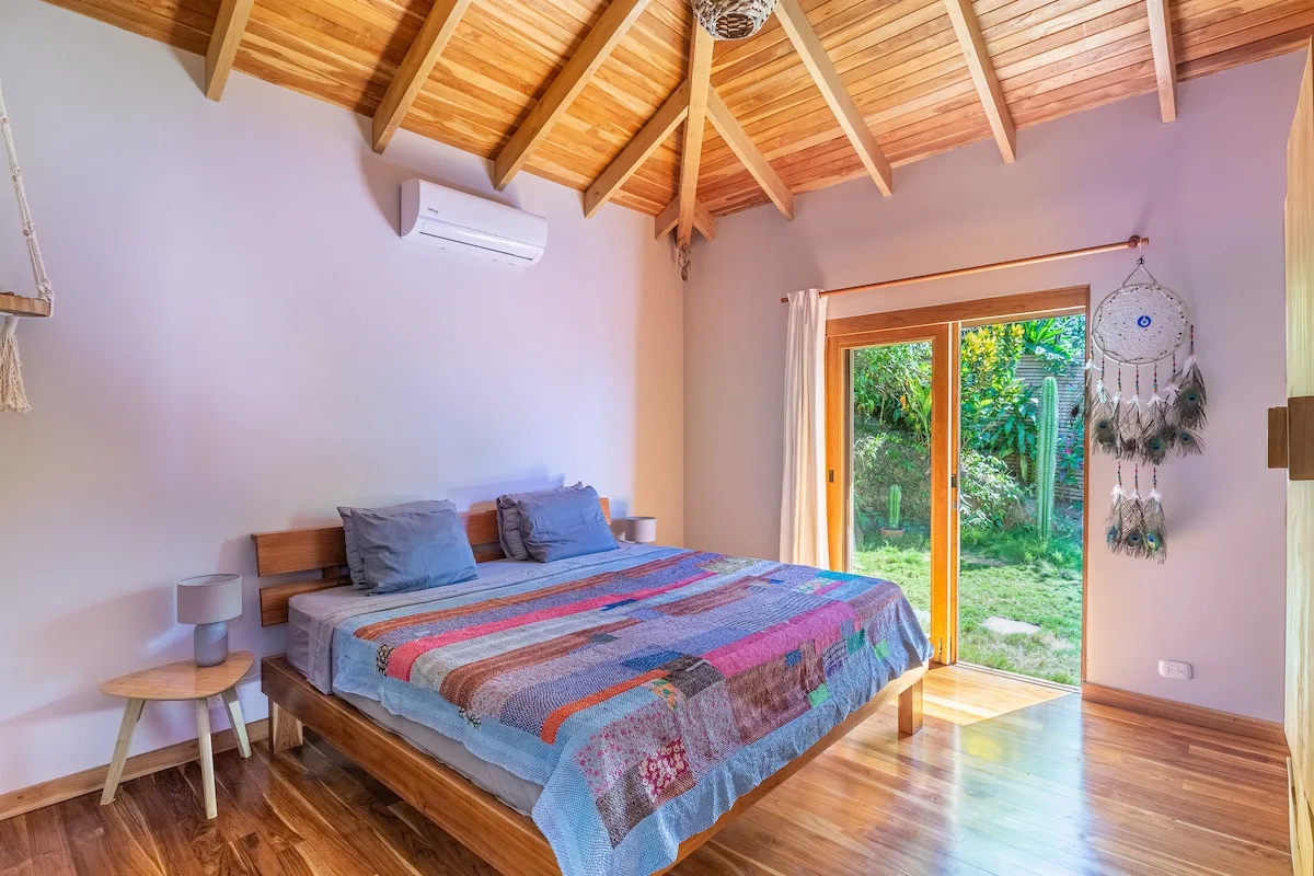 Un dormitorio con una cama de madera y una puerta de vidrio que da a la vegetación.