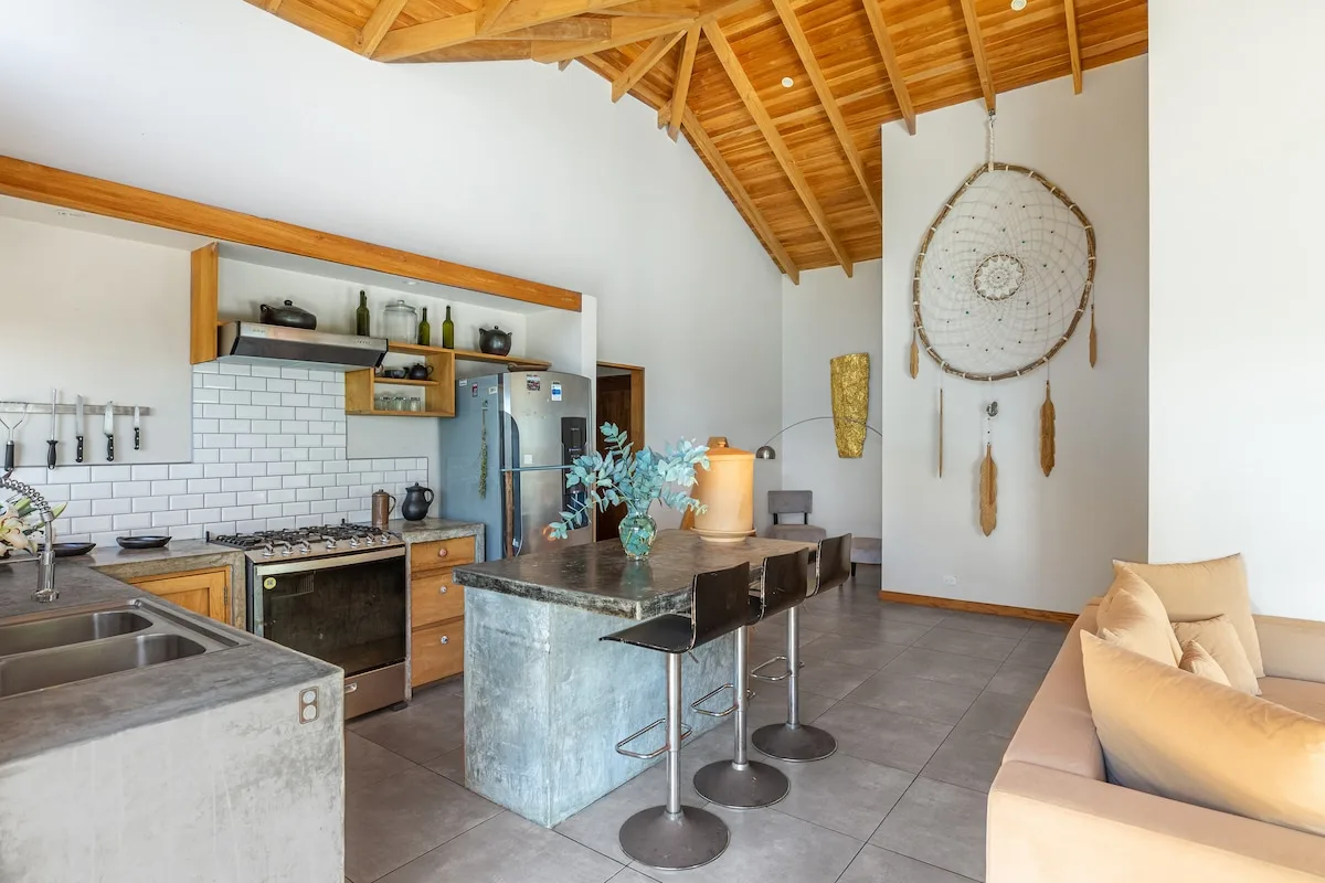 Una cocina amplia con una isla central, vigas de madera expuestas y una zona de estar contigua.