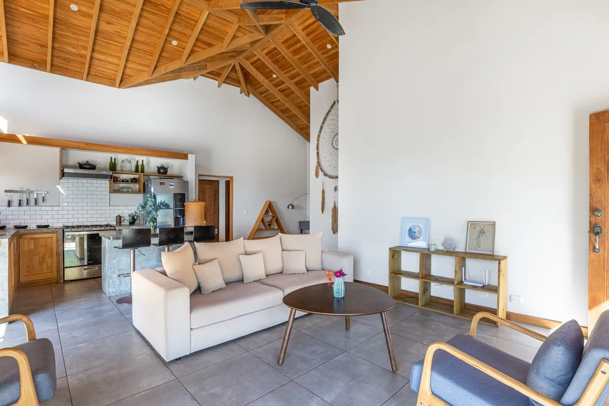 Una sala de estar luminosa con sofá, mesa de centro y cocina abierta.