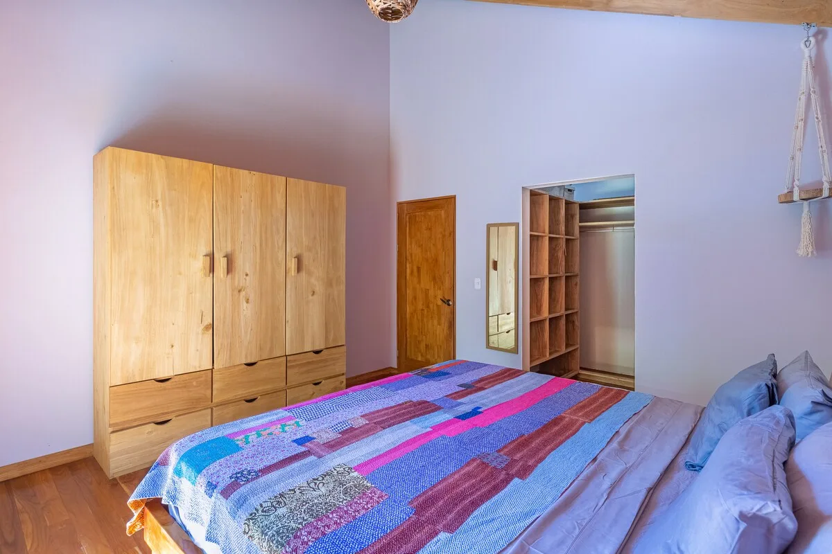 Un dormitorio con una colcha estampada de colores y un armario de madera.