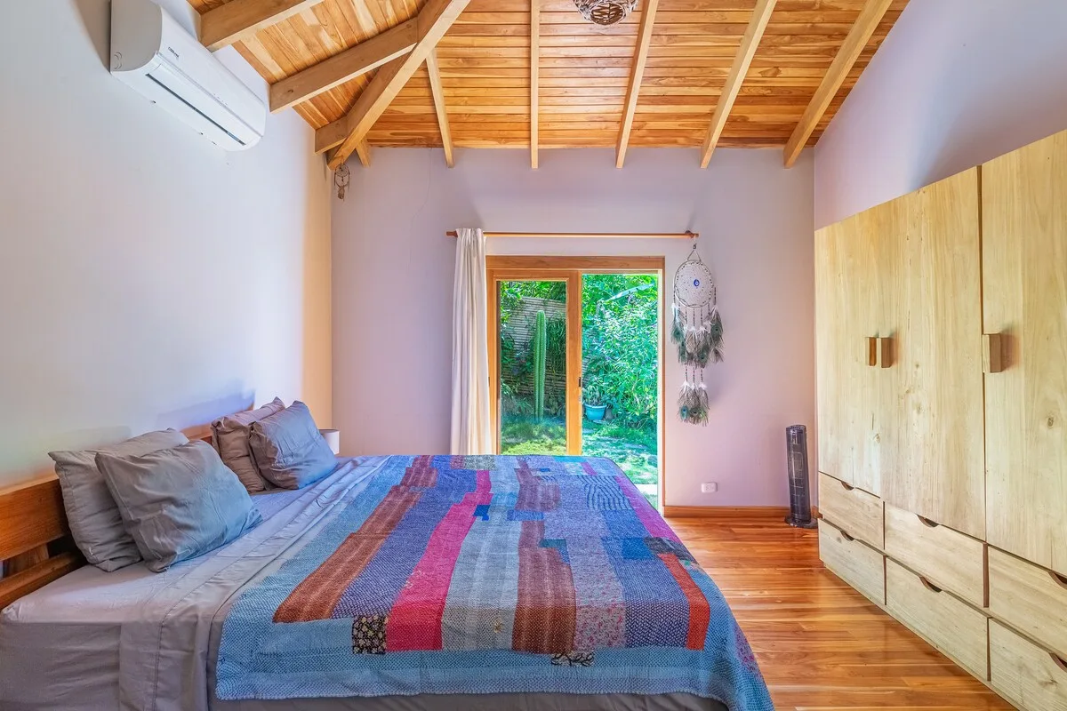 Un dormitorio con una cama frente a puertas de vidrio que dan a la vegetación.