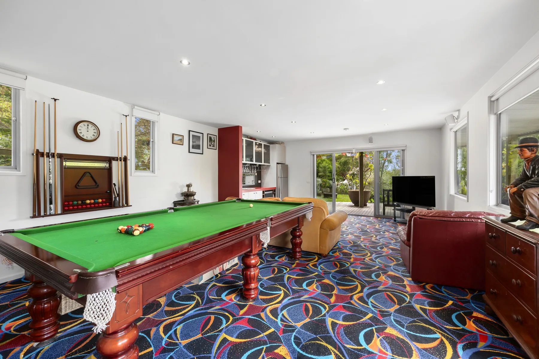 A games room features a green-felt pool table and colorful patterned carpet.
