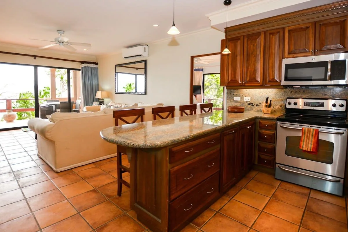 An open-plan kitchen and living area with a wood island and tiled floor.
