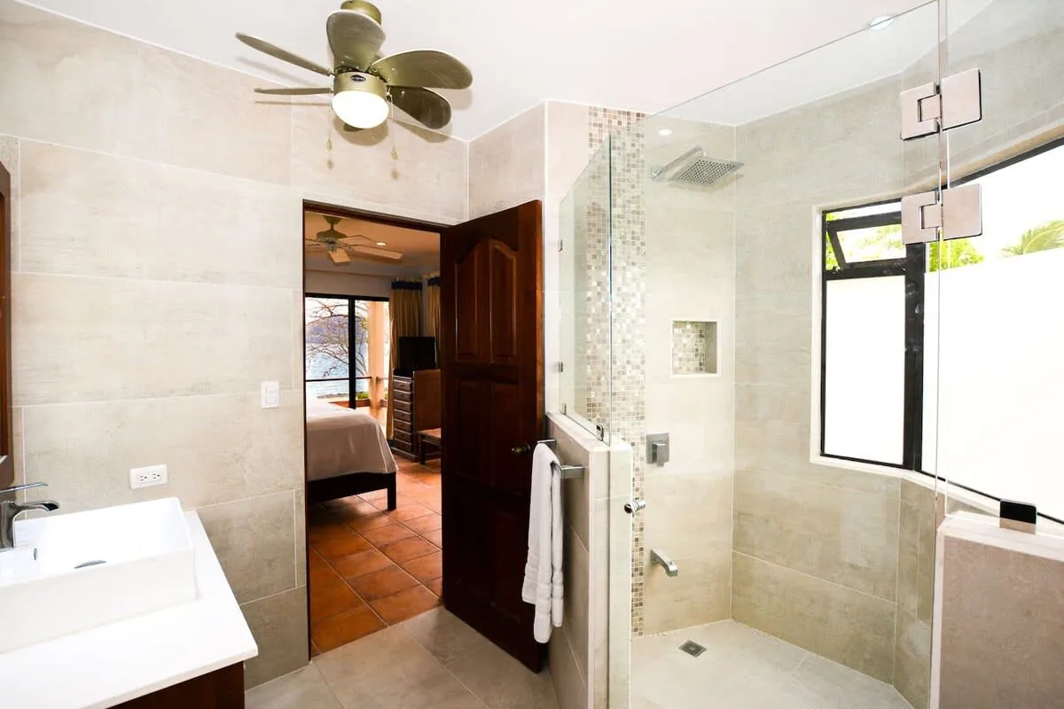 A tiled bathroom with a glass shower and a window.