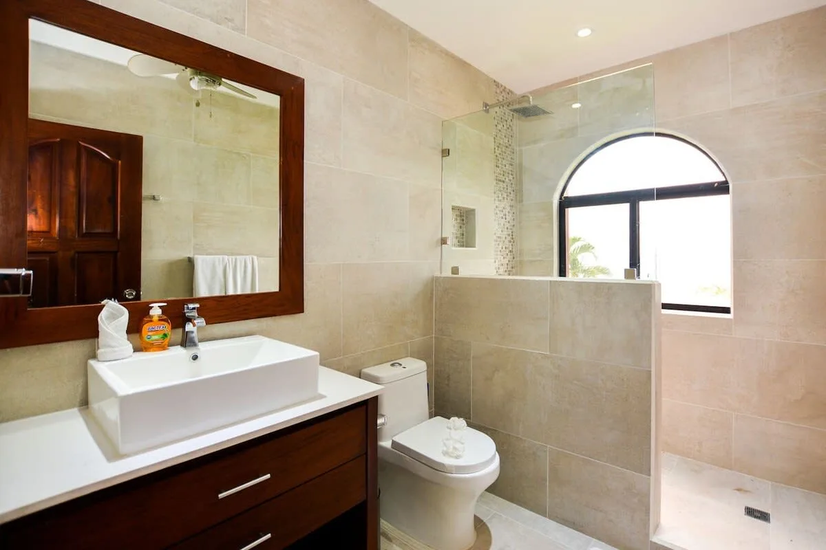 A tiled bathroom with a sink, toilet, and glass shower partition.