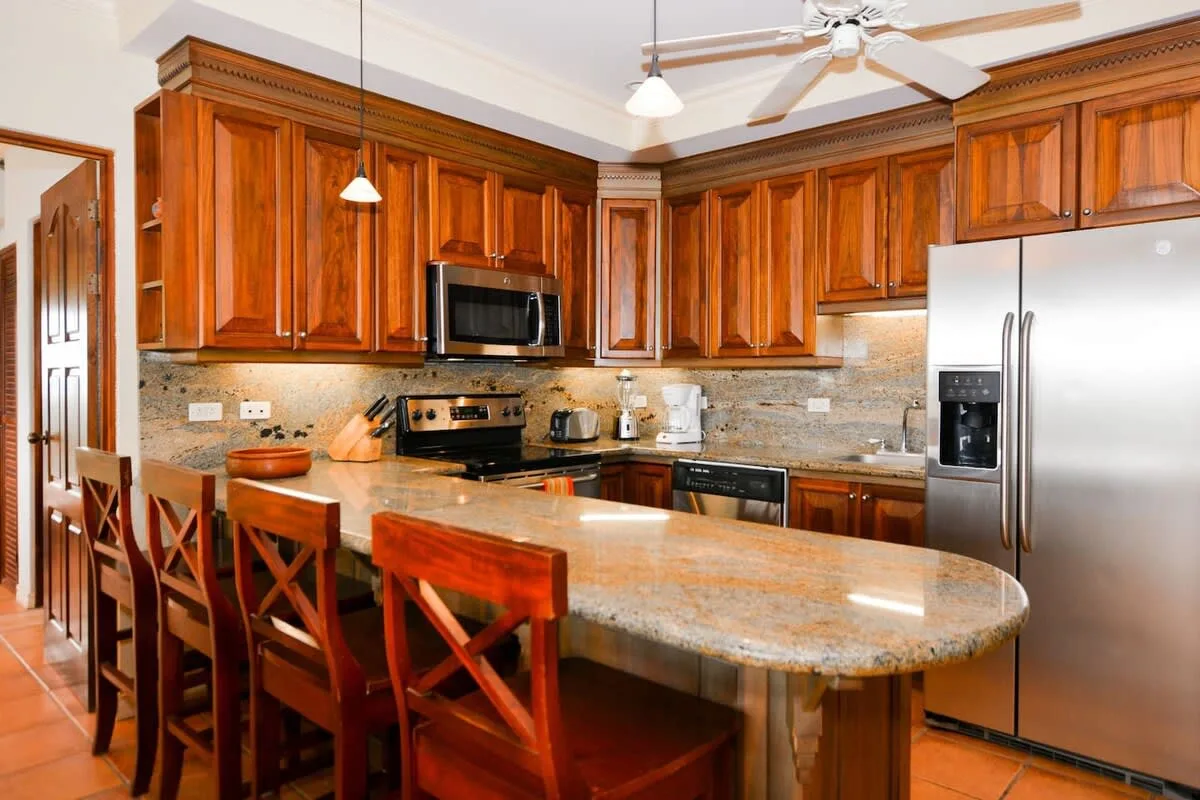 A kitchen with wood cabinets, stainless steel appliances, and a large island.