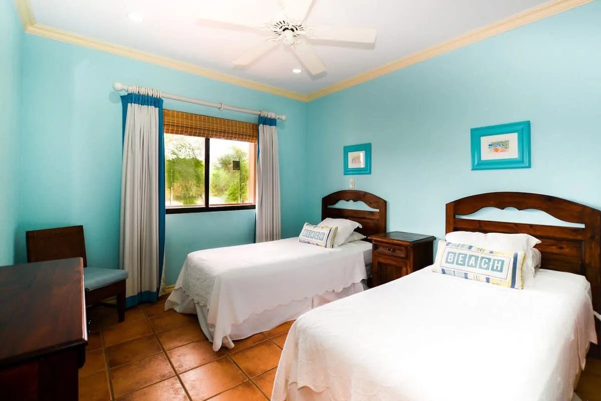 A turquoise bedroom with two beds and a window.