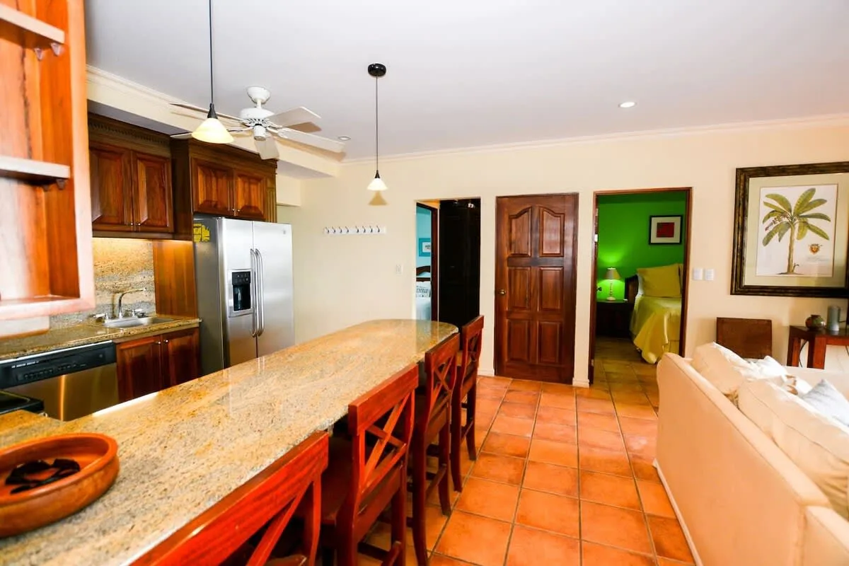 An open kitchen and dining area with a long counter, wooden seating, and adjoining doorways.