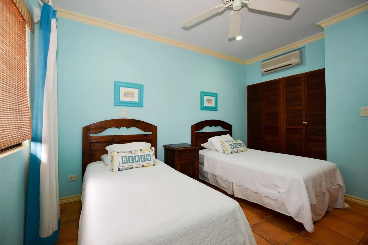 A bedroom with two single beds, dark wood headboards, and blue walls.