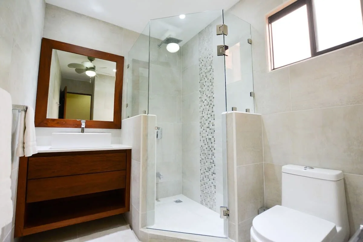 A bright bathroom with a glass shower and a vanity beneath a large mirror.