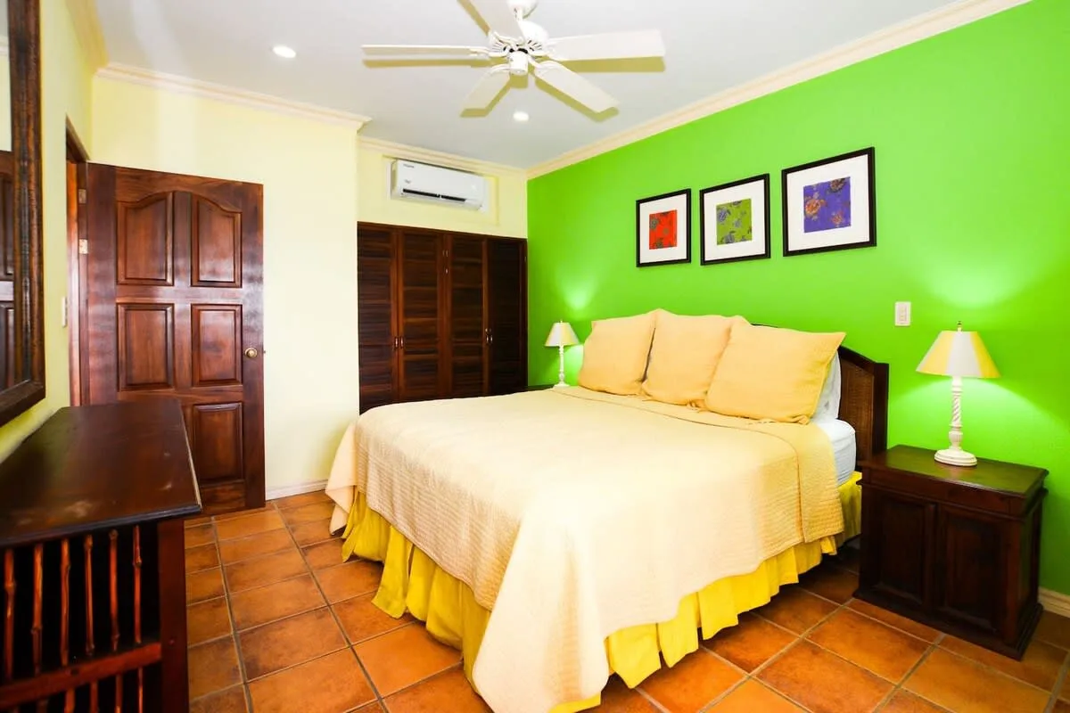 A bedroom with a bed, green accent wall, and framed artwork.