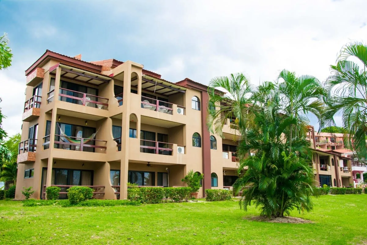 Shared amenity: A multi-story building stands behind a green lawn and palm trees.