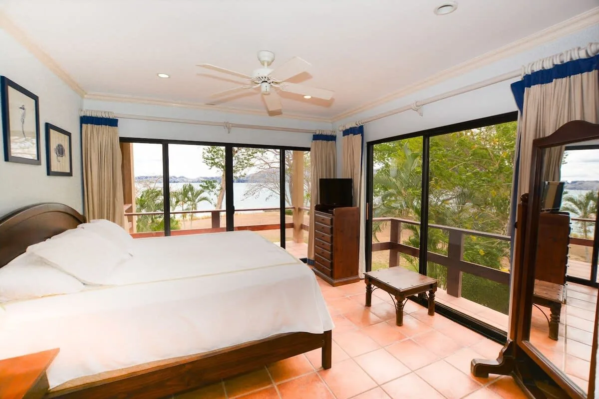 A bright bedroom opens onto a balcony through large glass doors.